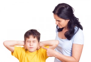 Mom talking to boy with hands over his ears