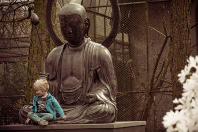 Little boy sitting on a buddha Statutes lap